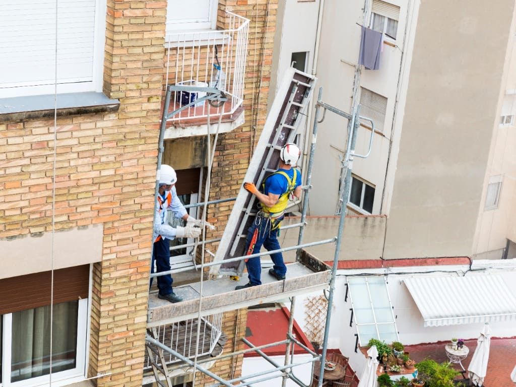 obreros suben escalera en andamio
